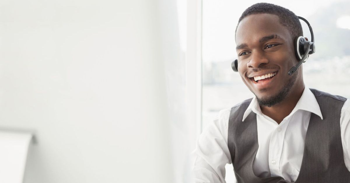 Smiling businessman with headset interacting in his office